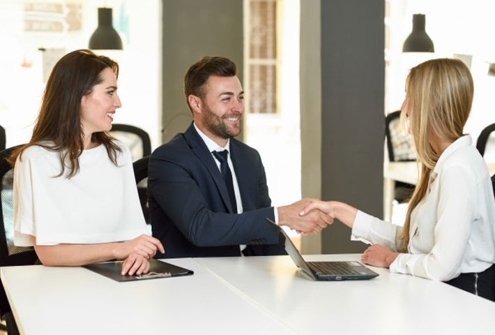 Smiling Young Couple Shaking  Hands With An Insurance Agent